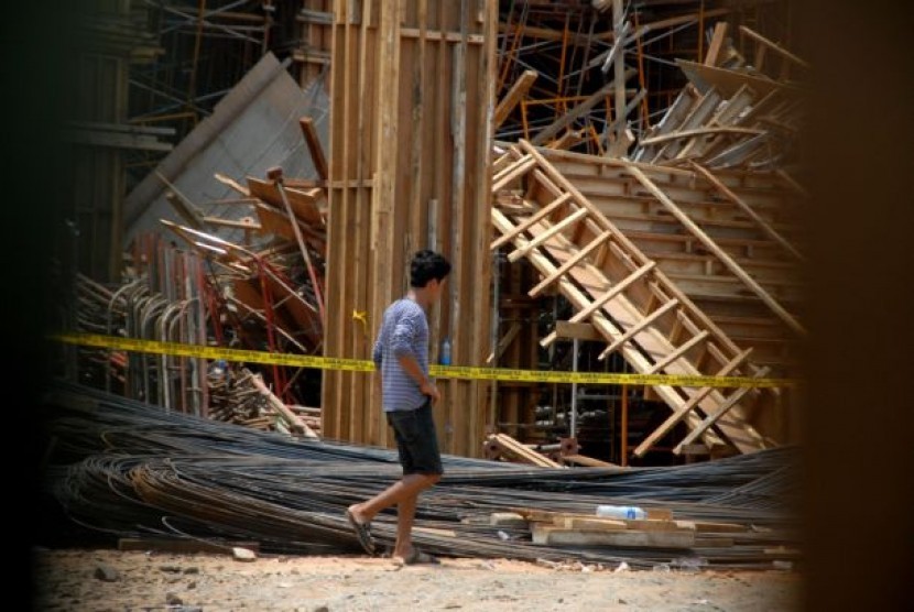 Pekerja melintas didepan konstruksi bangunan runtuh GOR Koja, Jakarta Utara, Jumat (20/9).