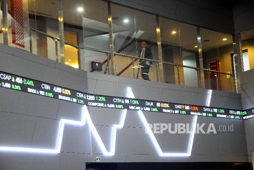 Pekerja melintas disamping layar pergerakan Indeks Harga Saham Gabungan (IHSG), Gedung Bursa Efek Indonesia (BEI) Jakarta, Selasa (18/4). 