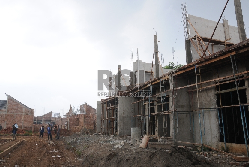  Pekerja melintas proyek pembangunan sebuah perumahan di Depok, Jawa Barat.