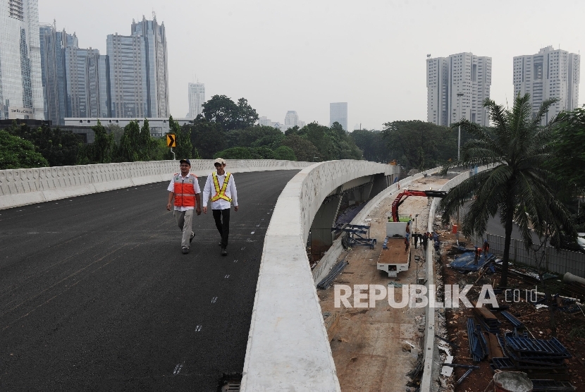 Pekerja melintas saat dilakukannya rangkaian uji coba Simpang Susun Semanggi di kawasan Semanggi, Jakarta, Kamis (13/7). 