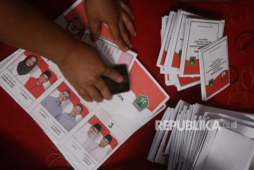 Pekerja melipat dan menyortir surat suara Pilkada Malang yang diikuti tiga pasangan calon di Kantor KPU Malang, Jawa Timur, Selasa (29/5).