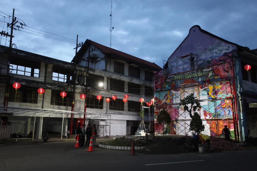Pekerja melukis mural di dinding bangunan di Jalan Kembang Jepun, Surabaya, Jawa Timur.