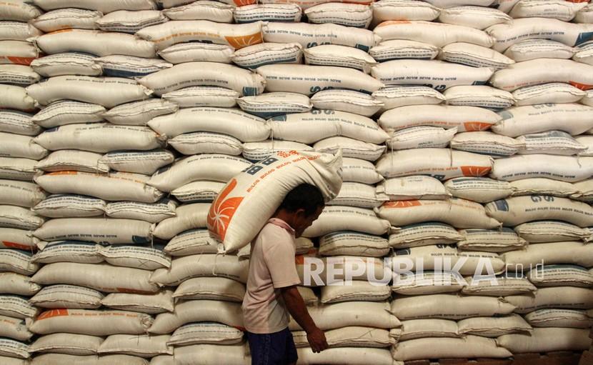 Pekerja memanggul karung berisi beras di gudang Bulog, Senin (21/3/2022). Bulog Sulselbar menyatakan stok beras mereka mencapai 100 ribu ton.
