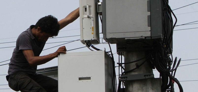 Pekerja memasang alat Remote Radio Unit (RRU) pada menara Base Transmitter System (BTS).