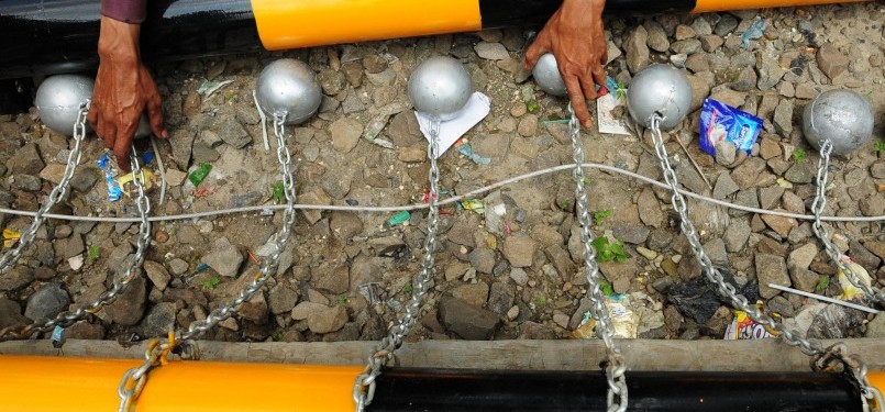 Pekerja memasang bola-bola besi penghalang penumpang atap gerbong kereta api di jalur kereta api Tambun-Bekasi, Bekasi, Jawa Barat, Selasa (17/1). (Republika/Aditya Pradana Putra)