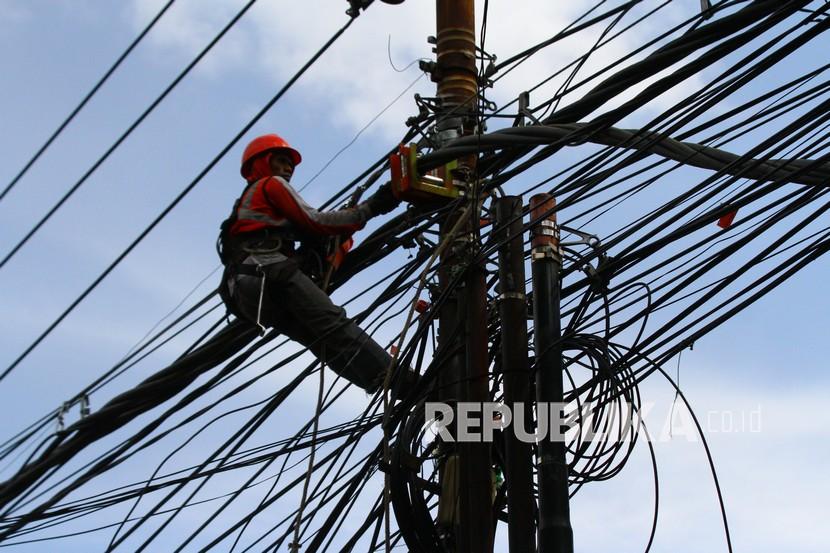 Pekerja memasang jaringan listrik untuk meningkatkan daya di sebuah kawasan pertokoan di Malang, Jawa Timur.