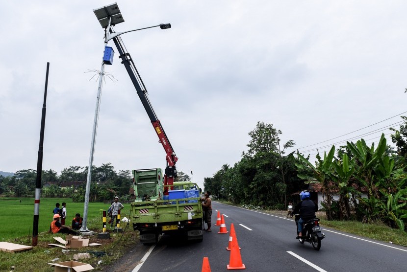 Pekerja memasang lampu penerangan jalan di jalur selatan kawasan Dayeuhluhur, Cilacap, Jawa Tengah, Selasa (30/5).