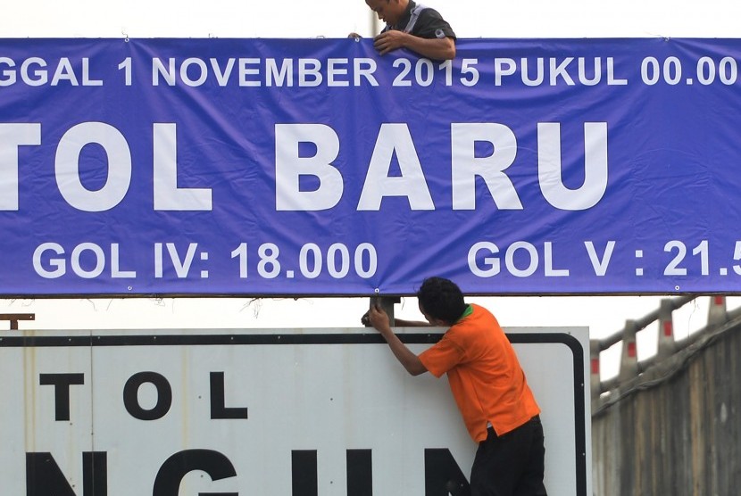 Pekerja memasang pengumuman penyesuaian tarif di pintu tol dalam kota, Jakarta, Sabtu (31/10). 