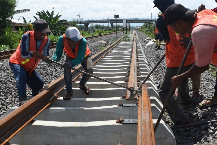 Pekerja memasang rel Kereta Api (KA) yang merupakan bagian dari pembangunan jalur ganda KA lintas selatan di Kota Madiun, Jawa Timur, Rabu (28/11/2018).