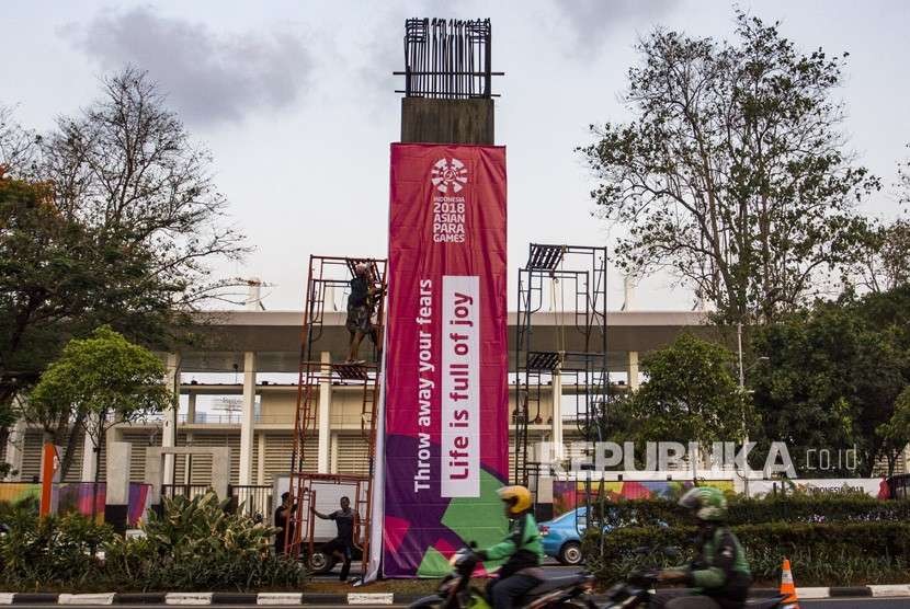 Pekerja memasang spanduk promosi Asian Para Games 2018 di kawasan Senayan, Jakarta, Selasa (2/10).