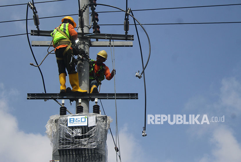 Pekerja memasang trafo penurun daya untuk distribusi listrik ke pelanggan.