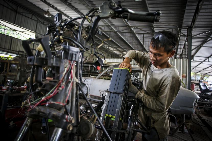 Pekerja memasukkan baterai saat mengonversi sepeda motor konvensional menjadi sepeda motor listrik di Lengkong, Tangerang Selatan, Banten, Kamis (15/9/2022). P