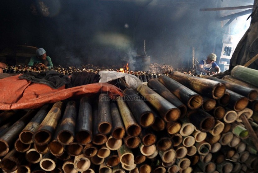 Pekerja membakar ketan lemang makanan tradisional Sumatera Barat di Jakarta, Rabu (2/7).(Republika/ Tahta Aidilla)