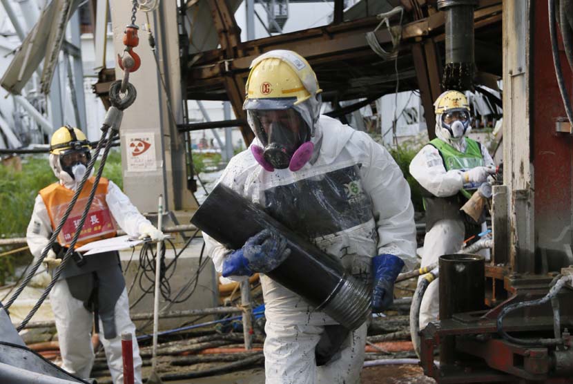 Pekerja membangun dinding pendingin PLTN Fukushima Daiichi yang rusak akibat terjangan tsunami di Okuma, Prefektur Fukushima, Tokyo, Jepang, Juli 2014. 