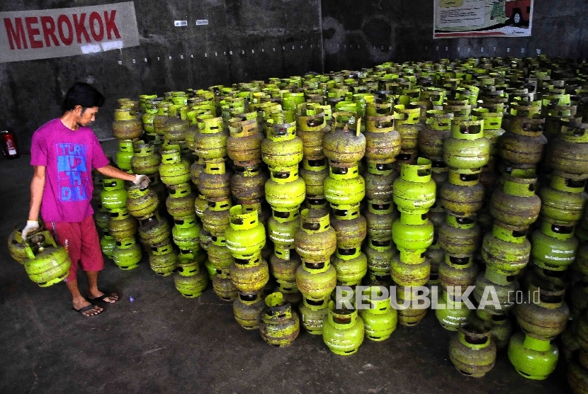 Pekerja membawa tabung gas elpiji tiga kilogram (gas melon) untuk dipindahkan ke truk pengangkut gas di agen penjualan gas, Mampang, Jakarta, Senin (31/10). 