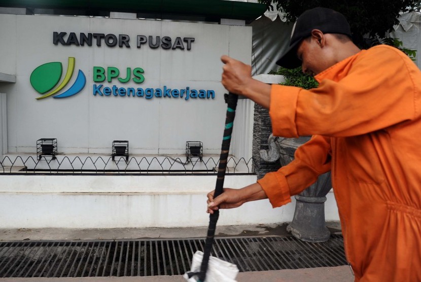 Pekerja membersihkan jalan didepan kantor Badan Penyelenggara Jaminan Kesehatan (BPJS) Ketenagakerjaan, Jakarta, Senin (6/7). 