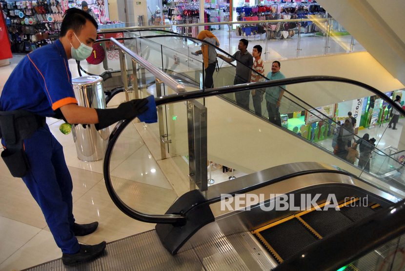 Pekerja membersihkan pegangan tangan tangga jalan dengan cairan disinfektan di pusat perbelanjaan Cibinong City Mall, Kabupaten Bogor, Jawa Barat, Sabtu, (14/3/2020).(Antara/Arif Firmansyah)