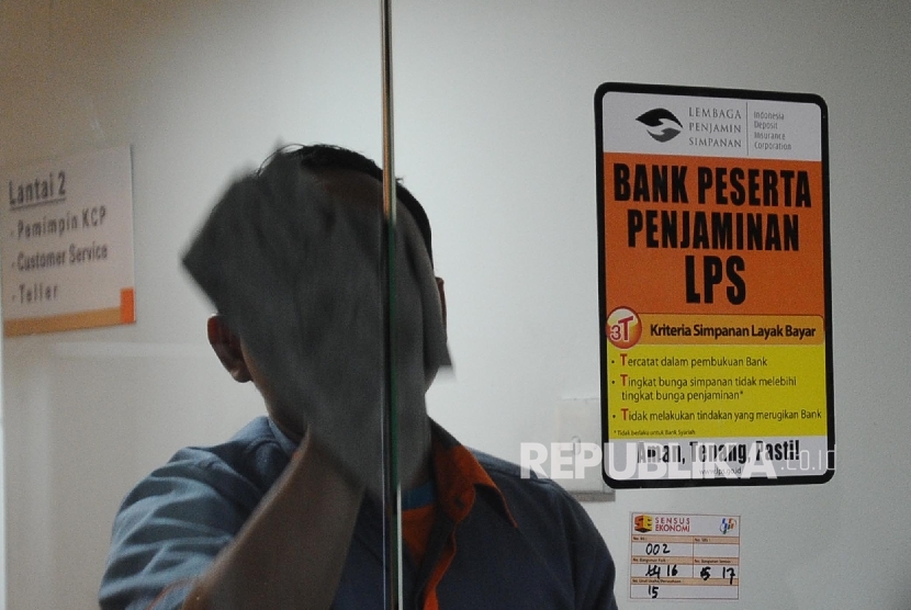 Pekerja membersihkan pintu kaca di salah satu Bank Peserta Penjaminan, Jakarta, Rabu (4\1)