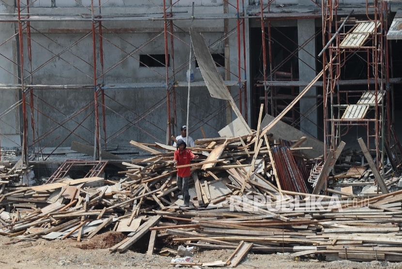 Pekerja membersihkan sisa kayu pada pembangunan Rusun yang dihentikan di kawasan Marunda, Jakarta Utara, Ahad (9/10).