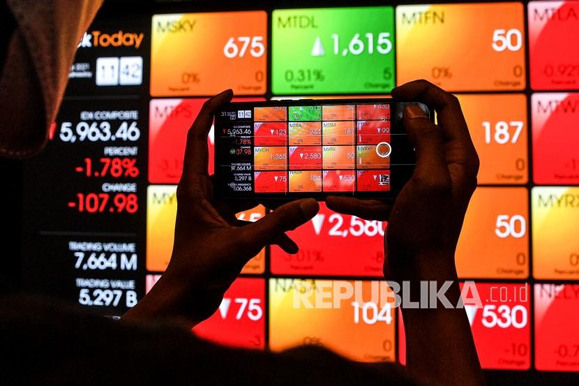 A passerby is taking a photo of the stock price announcement board of the Indonesian stock exchange 