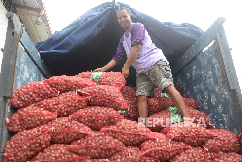 Pekerja memindahkan bawang merah yang siap dijual dalam operasi pasar di Gudang Bulog Divre Jakarta, Senin (16/5).
