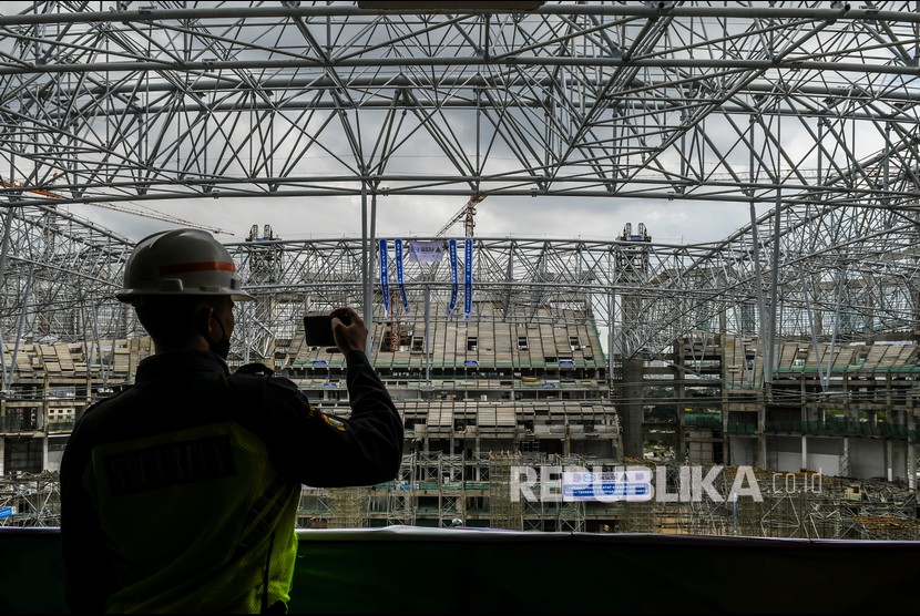 Pekerja memotret proses lifting rangka atap saat pembangunan Jakarta International Stadium (JIS) di Papanggo, Tanjung Priok, Jakarta, Rabu (16/6/2021). Pemasangan rangka atap JIS yang memiliki berat 3.900 ton dengan bentang 269 meter tersebut menggunakan sistem 