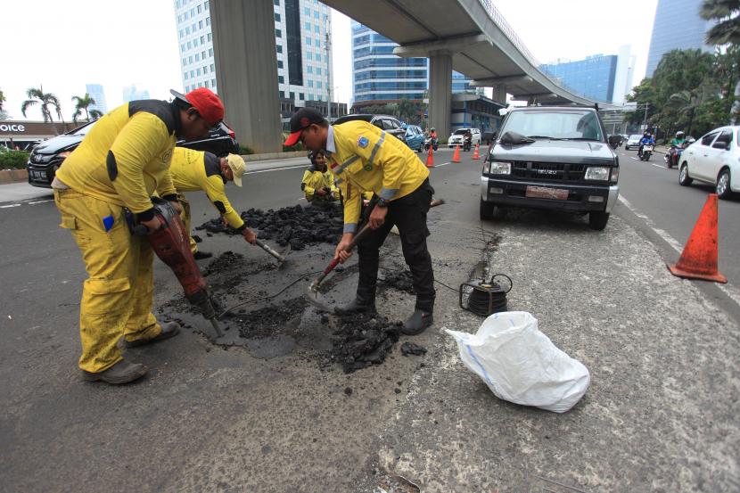 Pekerja memperbaiki jalan yang rusak di Jalan HR Rasuna Said, Jakarta Selatan, Rabu (19/10/2022). 