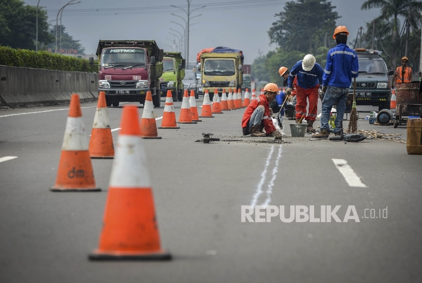  Pekerja memperbaiki jalan yang rusak di jalan tol Tangerang-Merak Kawasan Balaraja, Banten, Ahad (4/6).