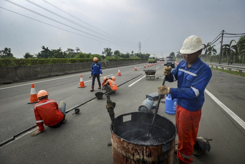 Pekerja memperbaiki jalan yang rusak di jalan tol Tangerang-Merak (ilustrasi)