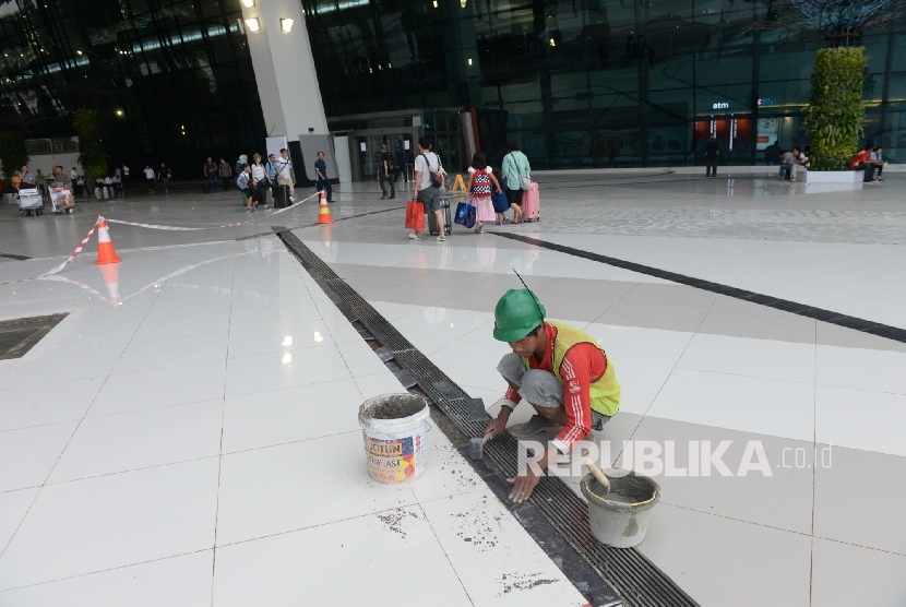 Pekerja memperbaiki lantai halaman Terminal 3 Ultimate pascabanjir, Bandara Soekarno-Hatta, Banten, Senin (15/8). (Republika/ Wihdan)