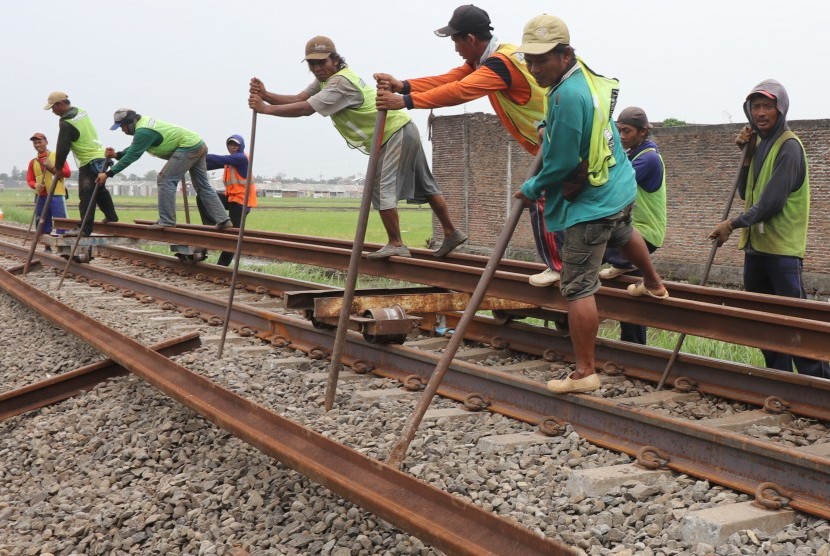 Pekerja mempersiapkan pemasangan besi rel kereta api 