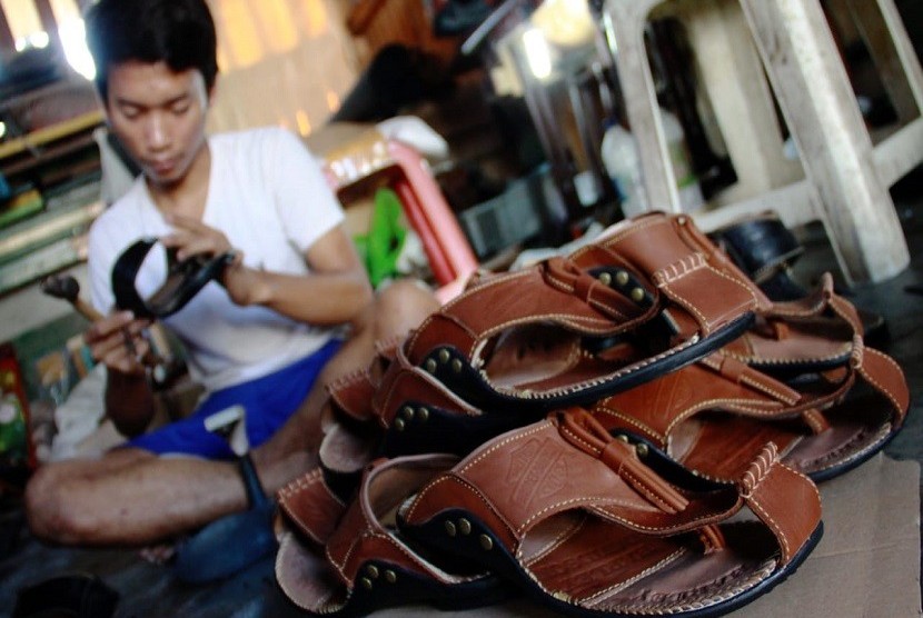 Pekerja memproduksi sepatu dan sandal kulit di bengkel rumahan Sentra Kerajinan Kulit Tanggulangin, Sidoarjo.