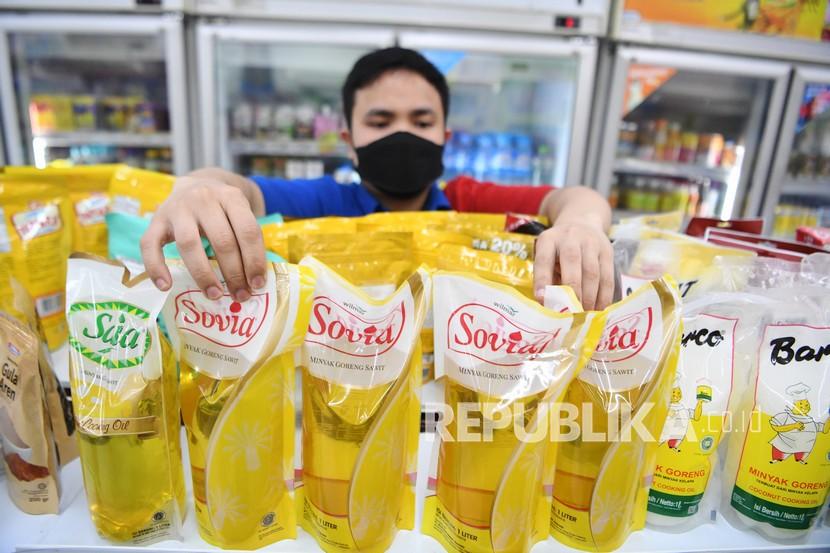 Pekerja menata minyak goreng kemasan yang dijual di salah satu minimarket di Jakarta, Rabu (19/1/2022). Menteri Perdagangan Muhammad Lutfi menetapkan kebijakan satu harga minyak goreng kemasan yakni Rp14.000 per liter yang dijual di minimarket mulai Rabu (19/1/2022).