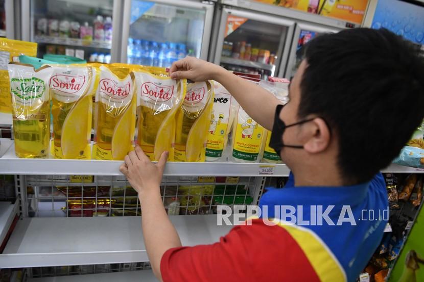 Pekerja menata minyak goreng kemasan yang dijual di salah satu minimarket di Jakarta, Rabu (19/1/2022). Menteri Perdagangan Muhammad Lutfi menetapkan kebijakan satu harga minyak goreng kemasan yakni Rp14.000 per liter yang dijual di minimarket mulai Rabu (19/1/2022). 
