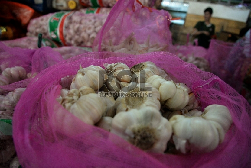 Pekerja menata tumpukan bawang putih di pasar tradisional. ilustrasi