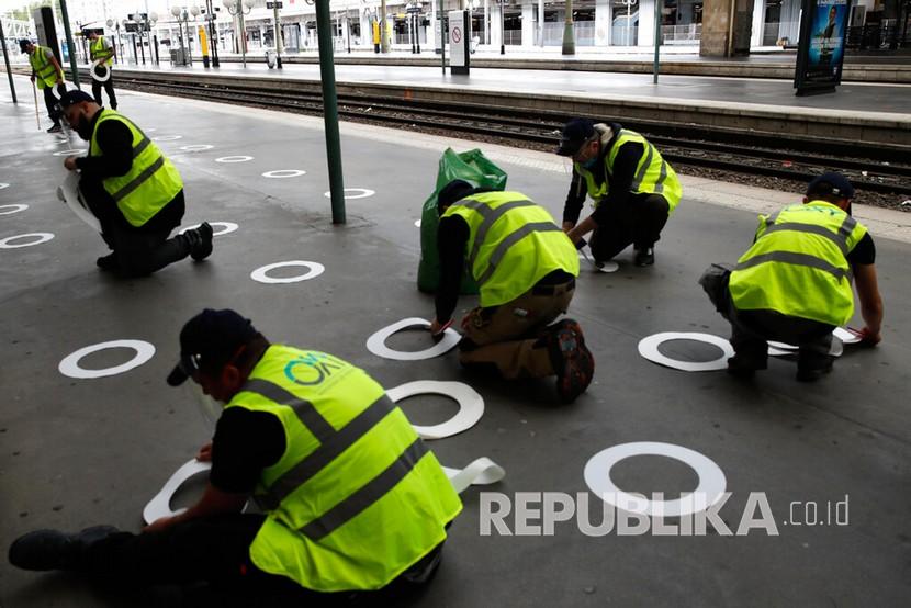 Pekerja menempelkan lingkaran tanda jarak sosial di stasiun kereta Gare du Nord di Paris, Senin (4/5). Prancis bersiap untuk menerapkan lockdown nasional pada 11 Mei 2020.