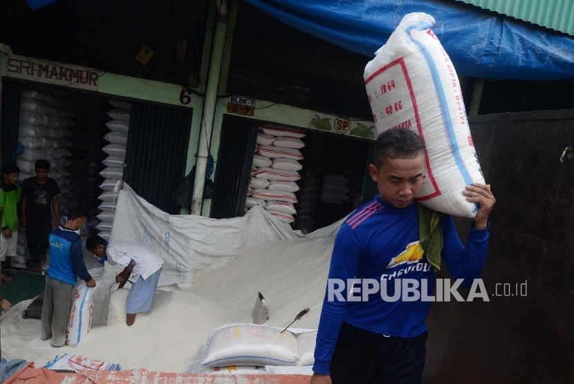 Pekerja mengangkat karung beras di Pasar Induk Beras Cipinang, Jakarta Timur, Kamis (13/4).
