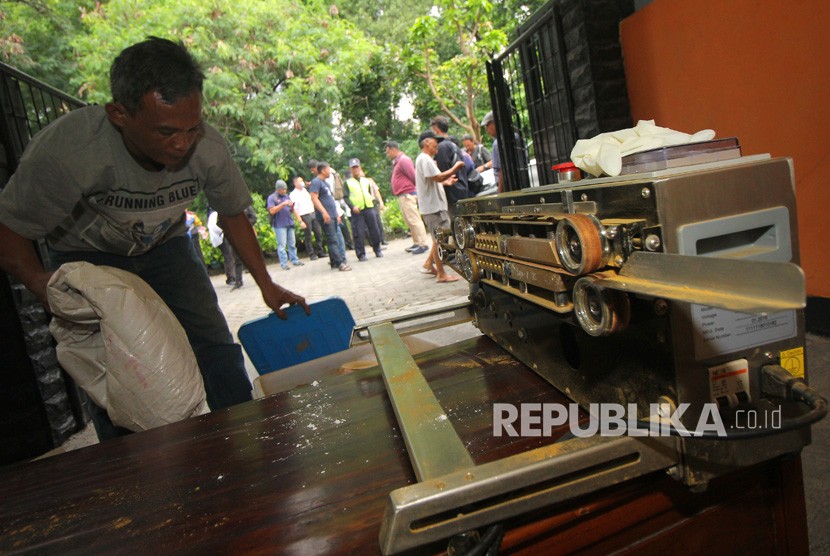 Pekerja mengangkut barang bukti saat penggerebekan rumah produksi jamu kuat ilegal di Babatan Pilang, Surabaya, Jawa Timur, Senin (24/2/2020).