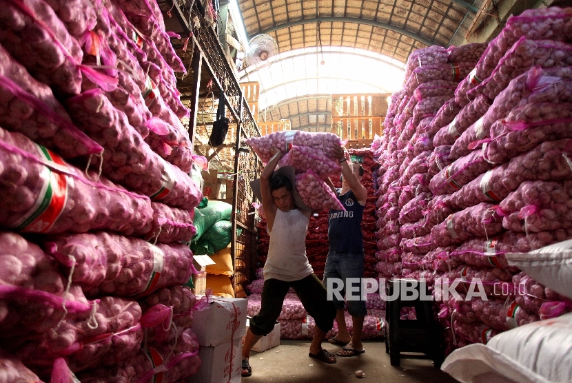 A worker helped the porter to carry a sack of garlic in Kramat Jati wholesale market, Jakarta, Wednesday (May 17).