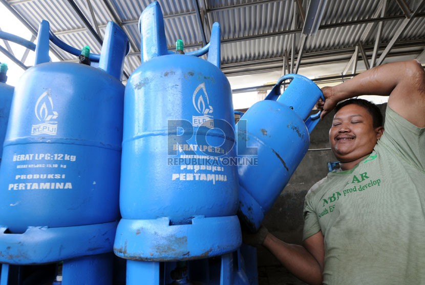 A worker carries a cylinder of Liquefied Petroleum Gas or LPG. (File photo)