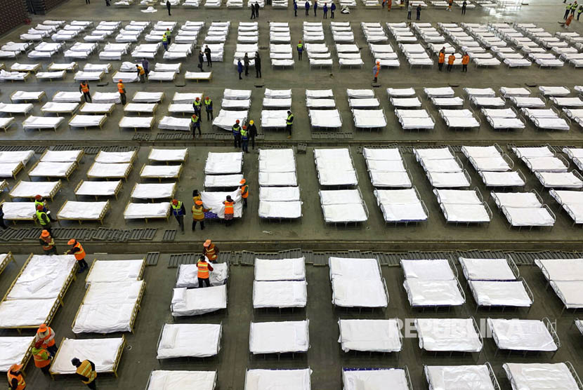 Pekerja mengatur deretan tempat tidur di sebuah gedung convention center yang disulap menjadi rumah sakit sementara di Wuhan, Hubei China, Selasa (4/1)