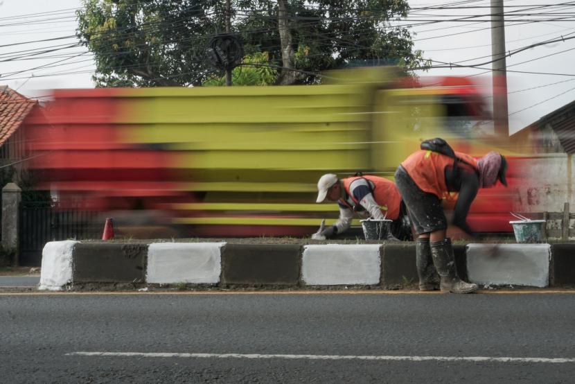 Pekerja mengecat median jalan di jalur pantura Kabupaten Batang, Jawa Tengah, Selasa (12/4/2022). Pengecatan median jalan untuk memberikan keamanan dan kenyamanan bagi pengendara yang melintas terlebih pada malam hari saat arus mudik dan balik Lebaran mendatang.