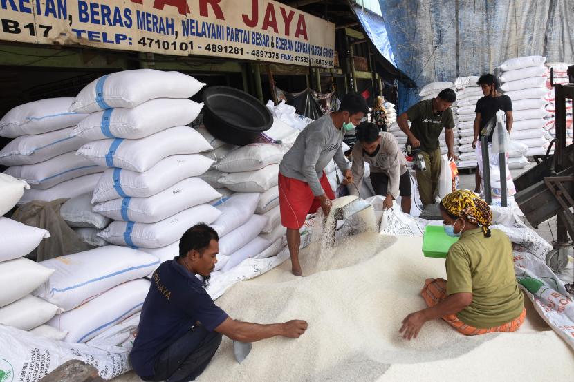 Pekerja mengemas beras ke dalam karung di Pasar Induk Beras Cipinang, Jakarta, Selasa (26/1/2021). 