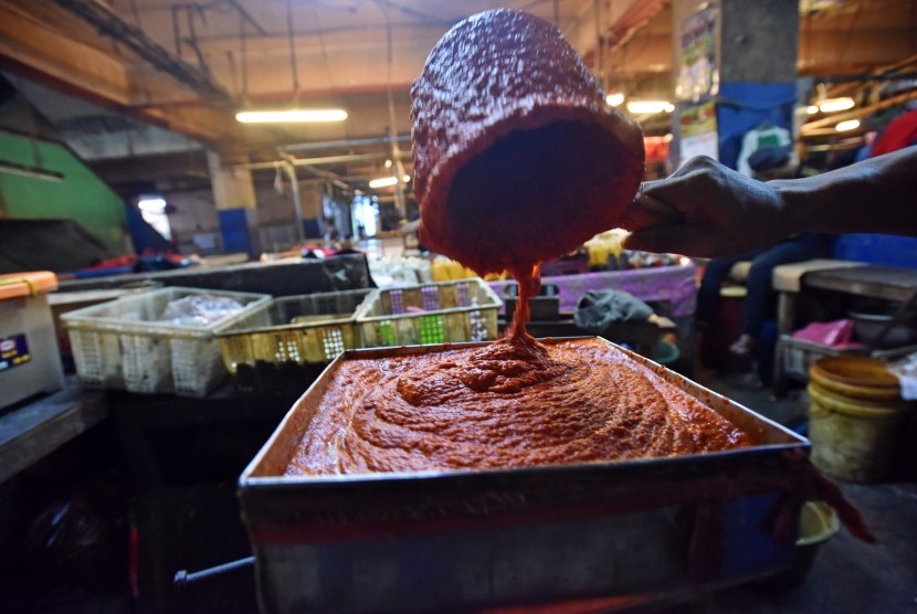 Pekerja menggiling cabai yang merupakan salah satu bahan baku bumbu masak jadi di Pasar Palmerah, Jakarta, Jumat (6/1). 