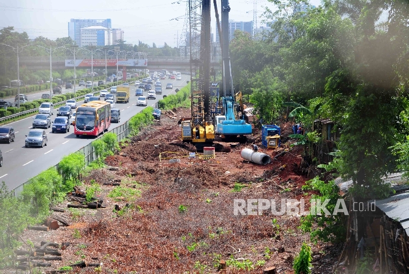 Pekerja menggunakan alat berat memasang tiang beton pada proyek pembangunan jalur kereta ringan atau Light Rail Transit (LRT) di sisi jalan Tol Cililitan, Jakarta, Ahad (17/4).  (Republika/Agung Supriyanto)