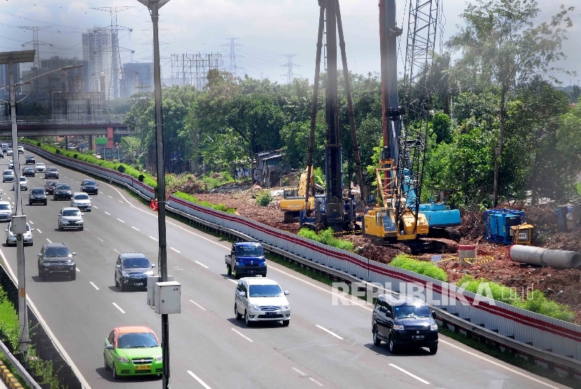 Pekerja menggunakan alat berat memasang tiang beton pada proyek pembangunan jalur kereta ringan atau Light Rail Transit (LRT) di sisi jalan Tol Cililitan, Jakarta, Ahad (17/4).  (Republika/Agung Supriyanto)