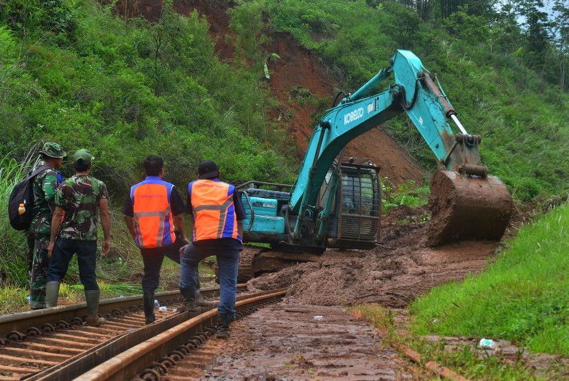 Pekerja menggunakan alat berat untuk membersihkan material tanah longsor yang menimbun jalur kereta api di KM 231+01 Malangbong, Kabupaten Garut, Jawa Barat, Kamis (23/11).