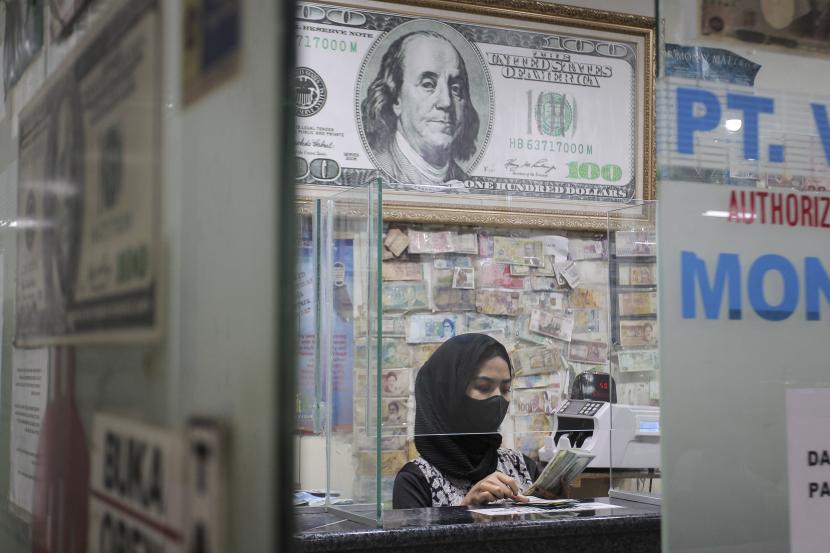 Pekerja menghitung uang dolar AS di salah satu gerai penukaran mata uang di Jakarta, Rabu (5/1/2022). 