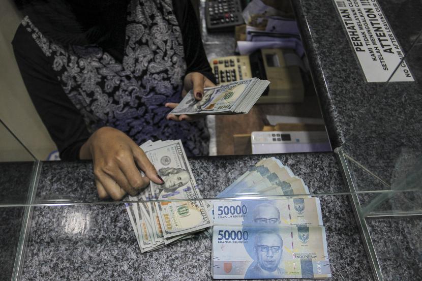 Pekerja menghitung uang dolar AS di salah satu gerai penukaran mata uang di Jakarta, Rabu (5/1/2022).
