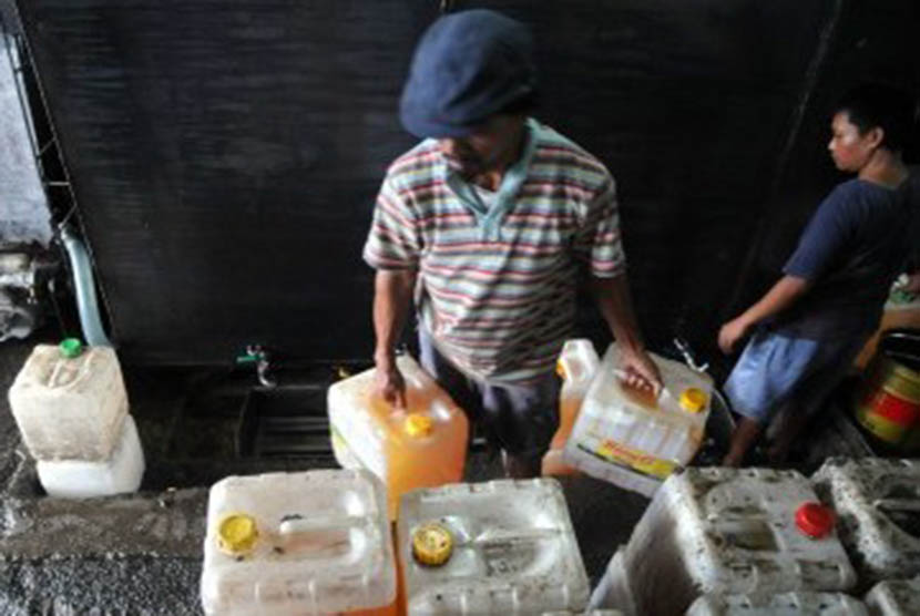 Pekerja mengisi jeriken minyak goreng curah di Pasar Tanah Abang, Jakarta, Rabu (11/1). (Republika/Wihdan Hidayat)